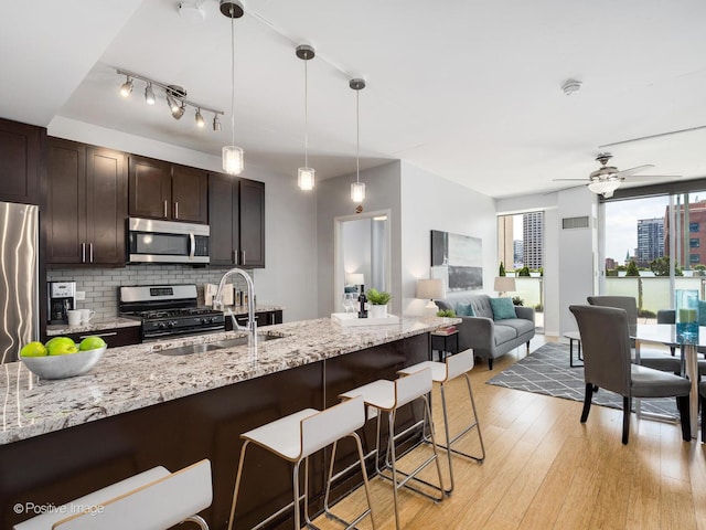 659 W Randolph St Unit 421, Chicago, IL 60661 - kitchen with stainless steel appliances, a breakfast bar, decorative backsplash, dark brown cabinets, and pendant lighting
