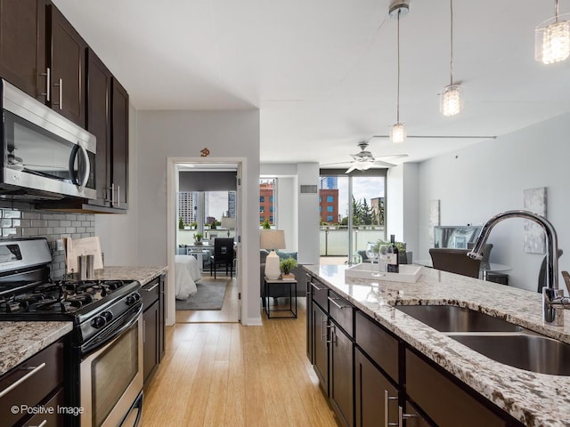 659 W Randolph St Unit 421, Chicago, IL 60661 - kitchen featuring stainless steel appliances, tasteful backsplash, light wood-style flooring, dark brown cabinets, and decorative light fixtures