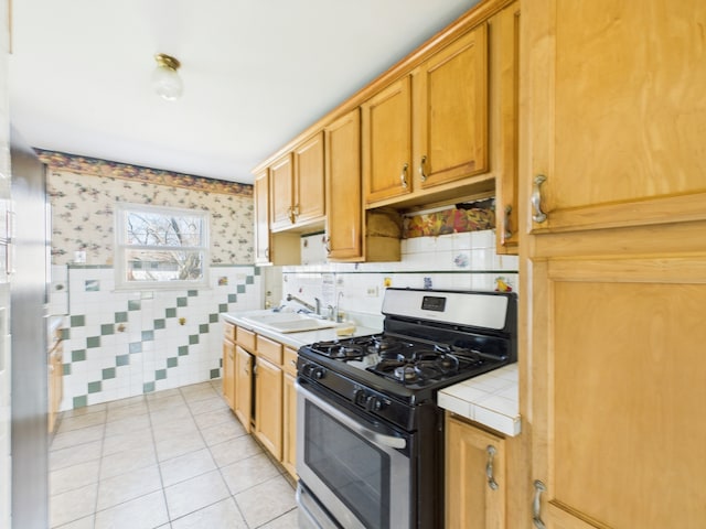 426 Norton Ave, Glendale Heights, IL 60139 - kitchen with stainless steel gas range oven, tile counters, light tile patterned flooring, wallpapered walls, and tile walls