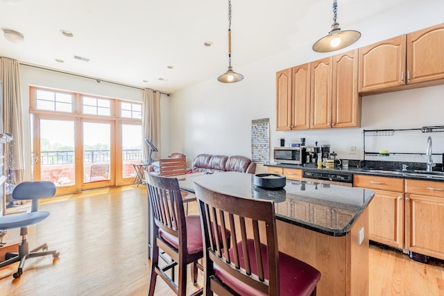1918 W Cermak Rd Unit 4, Chicago, IL 60608 - kitchen featuring a kitchen island, light wood finished floors, a kitchen bar, stainless steel microwave, and dark stone countertops