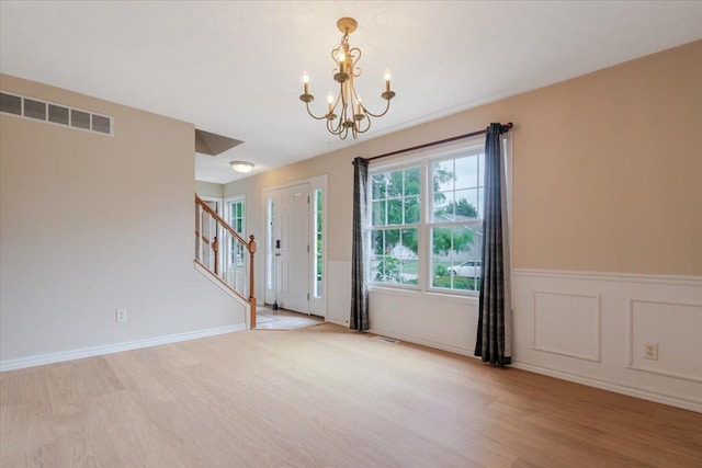 3310 Stonebridge Dr, Bloomington, IL 61704 - entryway featuring light wood-style flooring, stairs, a chandelier, and a wainscoted wall