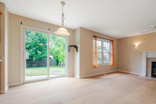 3310 Stonebridge Dr, Bloomington, IL 61704 - unfurnished living room featuring light wood finished floors, plenty of natural light, a tile fireplace, and ceiling fan