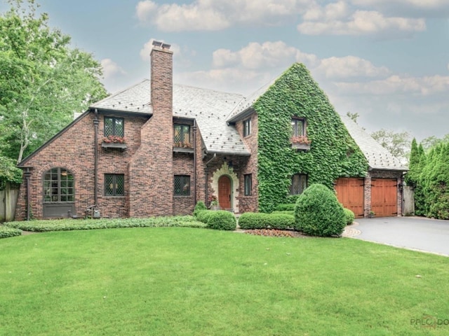 670 S Green Bay Rd, Lake Forest, IL 60045 - tudor home featuring concrete driveway, a high end roof, a chimney, and a front yard