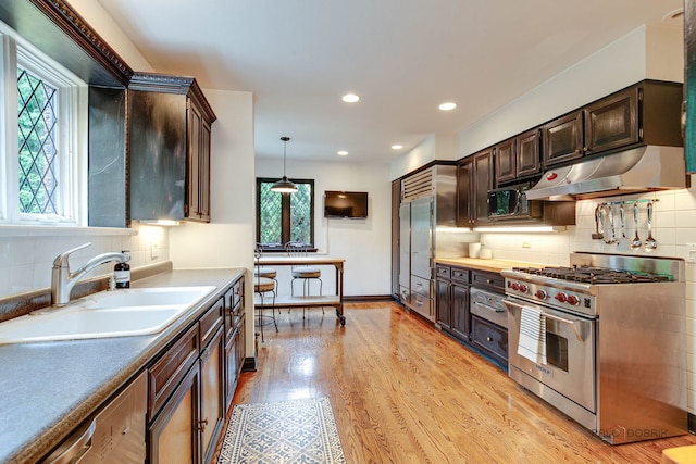 670 S Green Bay Rd, Lake Forest, IL 60045 - kitchen with high end appliances, under cabinet range hood, healthy amount of natural light, dark brown cabinetry, and recessed lighting