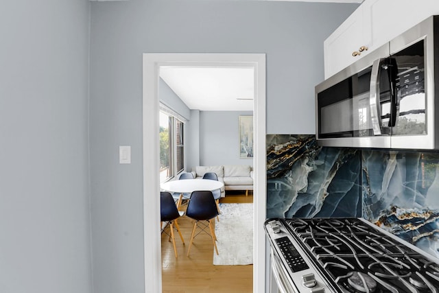 4880 N Marine Dr Unit 404, Chicago, IL 60640 - kitchen featuring appliances with stainless steel finishes, light wood-type flooring, white cabinets, and backsplash
