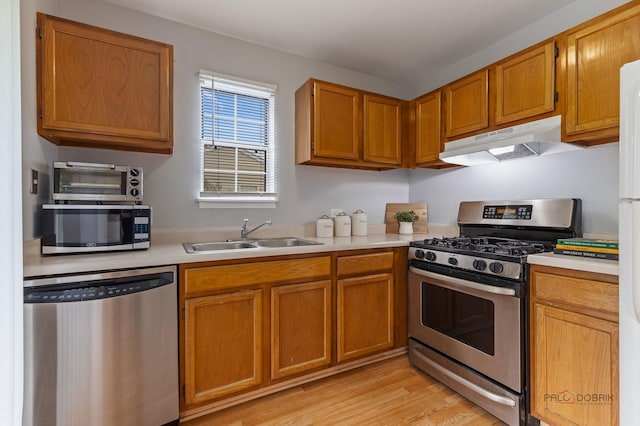 557 E Shag Bark Ln Unit H, Streamwood, IL 60107 - kitchen with stainless steel appliances, under cabinet range hood, light countertops, brown cabinets, and light wood-style flooring