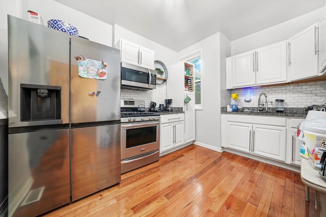 1516 E 74th Pl, Chicago, IL 60619 - kitchen with stainless steel appliances, backsplash, light wood-style flooring, white cabinets, and dark stone counters
