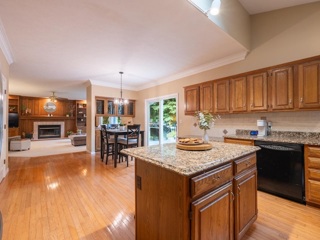 15955 Raintree Rd, Bloomington, IL 61705 - kitchen featuring black dishwasher, a center island, a tile fireplace, light wood-style flooring, and a chandelier