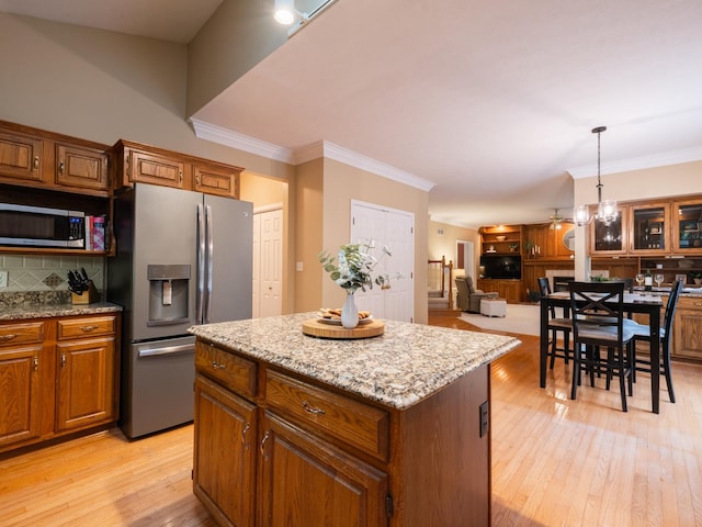 15955 Raintree Rd, Bloomington, IL 61705 - kitchen with stainless steel appliances, brown cabinetry, a kitchen island, decorative backsplash, and ornamental molding