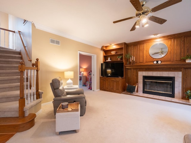 15955 Raintree Rd, Bloomington, IL 61705 - living area featuring carpet flooring, stairs, a ceiling fan, a tiled fireplace, and crown molding