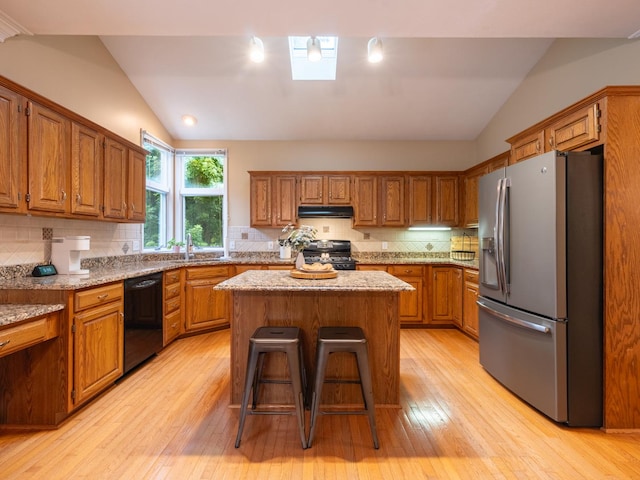 15955 Raintree Rd, Bloomington, IL 61705 - kitchen featuring black appliances, lofted ceiling, under cabinet range hood, a center island, and brown cabinets