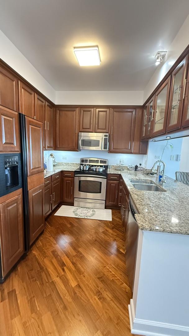 1841 S Calumet Ave Unit 2102, Chicago, IL 60616 - kitchen featuring appliances with stainless steel finishes, light stone counters, dark wood finished floors, and glass insert cabinets