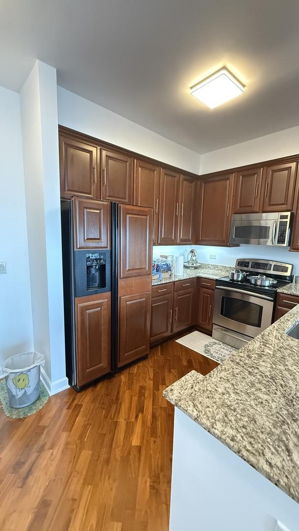 1841 S Calumet Ave Unit 2102, Chicago, IL 60616 - kitchen with stainless steel appliances, light stone countertops, dark brown cabinets, and dark wood-style floors