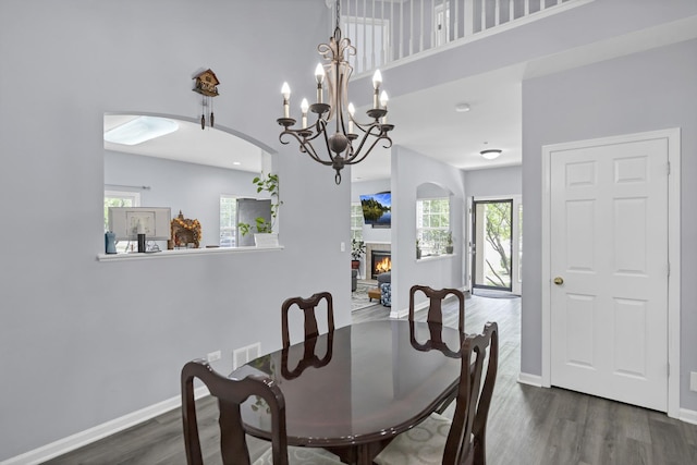 1850 Maureen Dr, Hoffman Estates, IL 60192 - dining area featuring wood finished floors, arched walkways, a glass covered fireplace, a high ceiling, and a chandelier