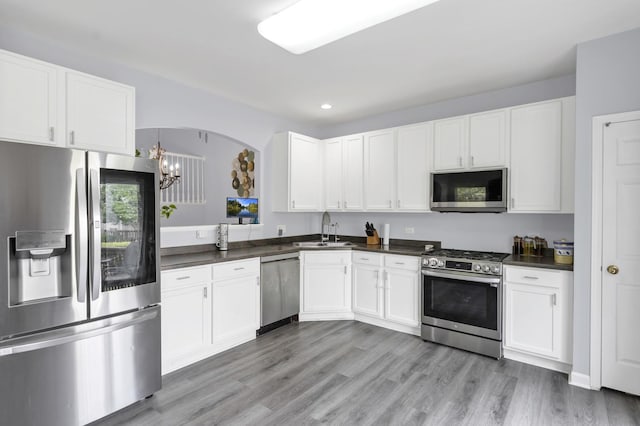 1850 Maureen Dr, Hoffman Estates, IL 60192 - kitchen featuring stainless steel appliances, dark countertops, a chandelier, light wood-style flooring, and white cabinetry