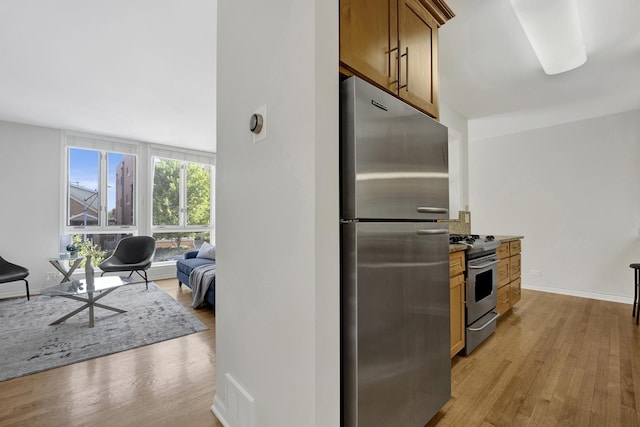 1315 W Webster Ave, Chicago, IL 60614 - kitchen featuring stainless steel appliances, light wood finished floors, open floor plan, brown cabinets, and stone countertops