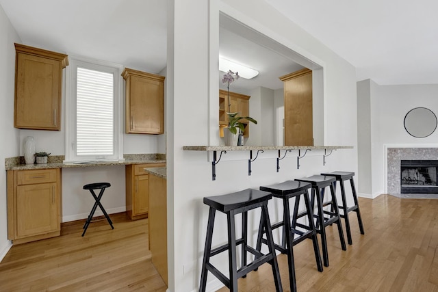 1315 W Webster Ave, Chicago, IL 60614 - kitchen featuring light wood finished floors, a kitchen breakfast bar, light stone countertops, and a tile fireplace