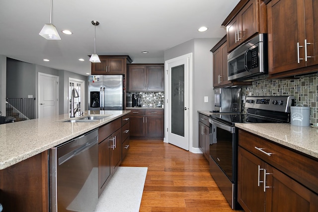 2225 Prairie Chase Dr, Bourbonnais, IL 60914 - kitchen featuring stainless steel appliances, decorative backsplash, decorative light fixtures, light stone counters, and light wood-type flooring