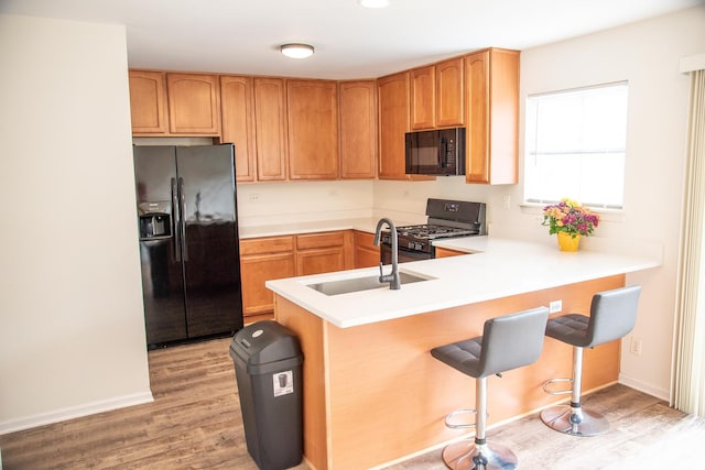 895 Clover Ln Unit 895, Pingree Grove, IL 60140 - kitchen with black appliances, light wood-type flooring, a breakfast bar, and a peninsula