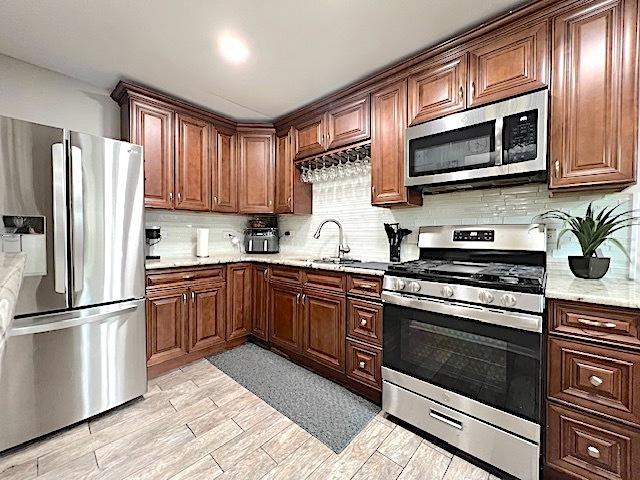 534 White Oak Rd, Bolingbrook, IL 60440 - kitchen featuring stainless steel appliances, decorative backsplash, light wood-style flooring, and light stone countertops