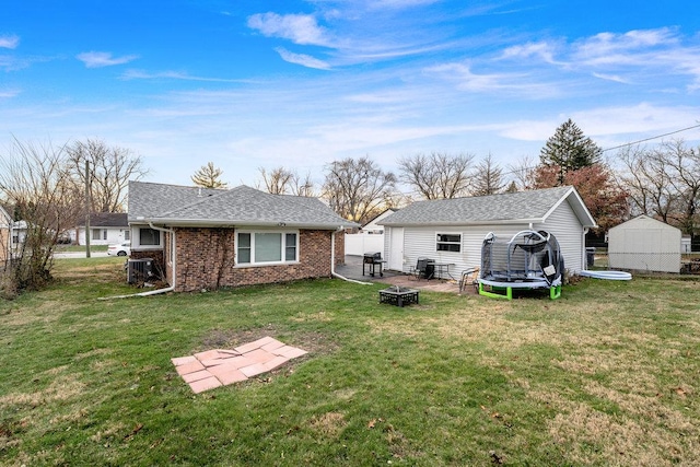 74 Marquette St, Park Forest, IL 60466 - rear view of house featuring a fire pit, a trampoline, an outbuilding, brick siding, and a shingled roof