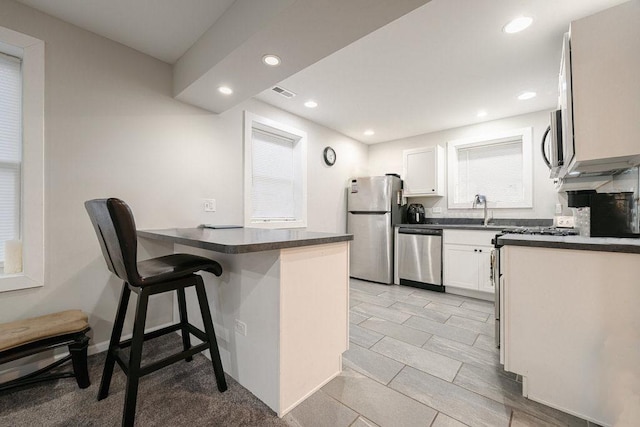 74 Marquette St, Park Forest, IL 60466 - kitchen with appliances with stainless steel finishes, dark countertops, a peninsula, recessed lighting, and white cabinetry