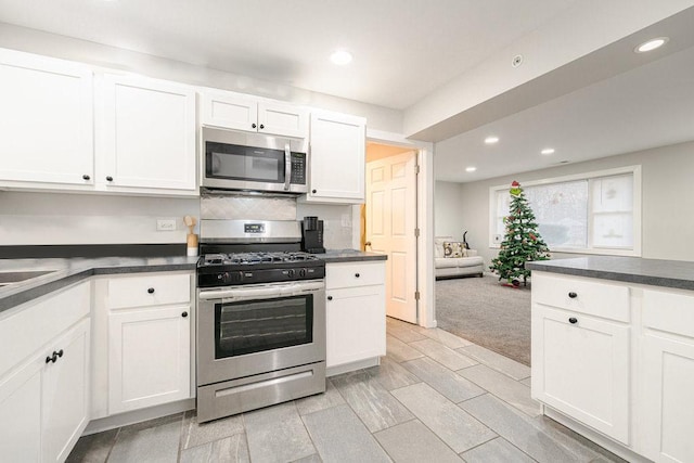 74 Marquette St, Park Forest, IL 60466 - kitchen with stainless steel appliances, recessed lighting, dark countertops, white cabinets, and light colored carpet
