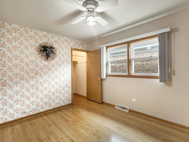 4841 N Natchez Ave, Chicago, IL 60656 - unfurnished bedroom with light wood finished floors, wallpapered walls, and ceiling fan