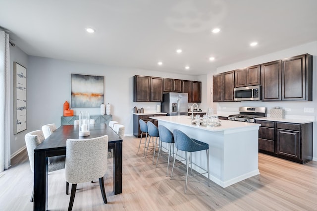 2893 Killarny Dr, Elgin, IL 60124 - kitchen featuring stainless steel appliances, light wood-style flooring, dark brown cabinetry, a breakfast bar area, and recessed lighting