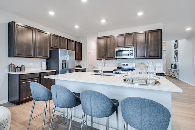 2893 Killarny Dr, Elgin, IL 60124 - kitchen with stainless steel appliances, dark brown cabinetry, light countertops, an island with sink, and a kitchen bar
