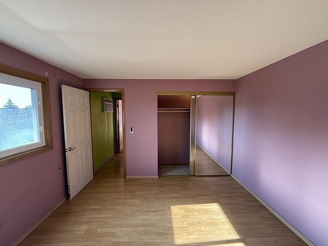 5925 W Montrose Ave Unit 3C, Chicago, IL 60634 - unfurnished bedroom with light wood-style flooring, a closet, and a wall mounted air conditioner