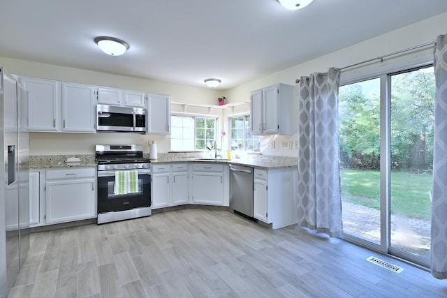 2020 Medinah Cir, Elgin, IL 60123 - kitchen featuring appliances with stainless steel finishes, light stone countertops, white cabinetry, and light wood-type flooring