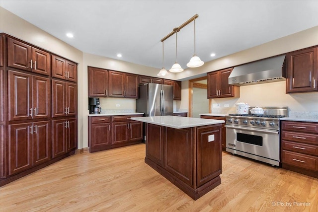 906 Ridgewood Dr, Cary, IL 60013 - kitchen featuring wall chimney exhaust hood, appliances with stainless steel finishes, light wood-style floors, a kitchen island, and hanging light fixtures