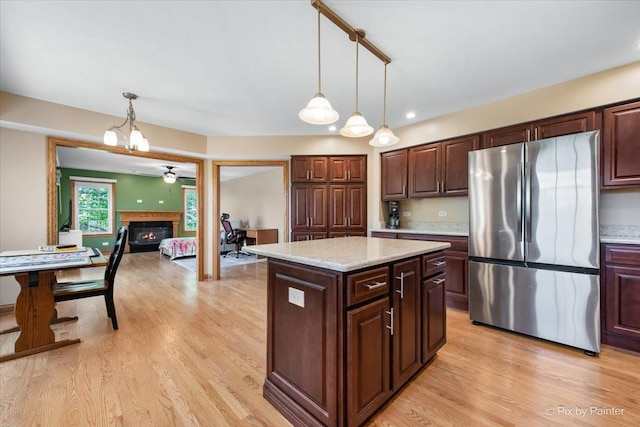 906 Ridgewood Dr, Cary, IL 60013 - kitchen with freestanding refrigerator, a glass covered fireplace, light wood-style flooring, hanging light fixtures, and recessed lighting