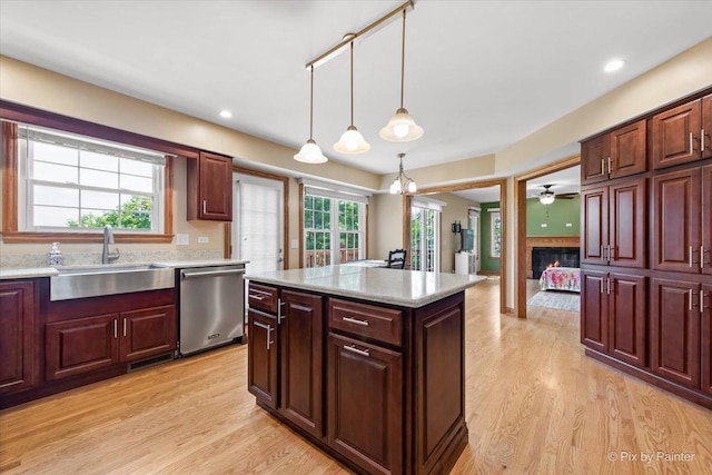 906 Ridgewood Dr, Cary, IL 60013 - kitchen with stainless steel dishwasher, a glass covered fireplace, light wood finished floors, decorative light fixtures, and a kitchen island