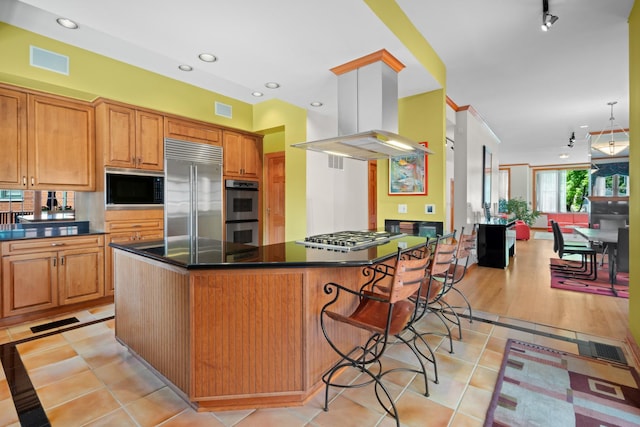 925 E 49th St, Chicago, IL 60615 - kitchen featuring built in appliances, island exhaust hood, dark countertops, a kitchen breakfast bar, and light tile patterned flooring