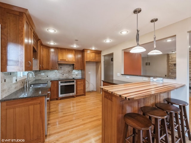 235 S Cedar St, Palatine, IL 60067 - kitchen featuring oven, brown cabinetry, light wood-style flooring, a kitchen breakfast bar, and decorative backsplash