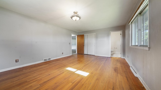 4209 Rotary Rd, Rockford, IL 61109 - unfurnished bedroom featuring light wood-style floors, a baseboard heating unit, and connected bathroom