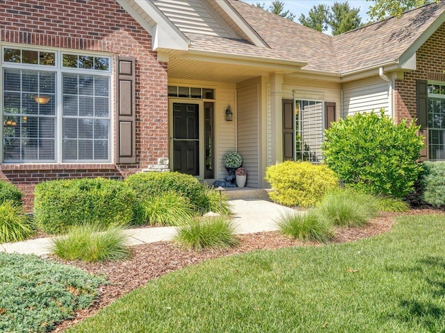 7681 Highlands Dr, Rockford, IL 61102 - view of exterior entry featuring brick siding, roof with shingles, and a yard