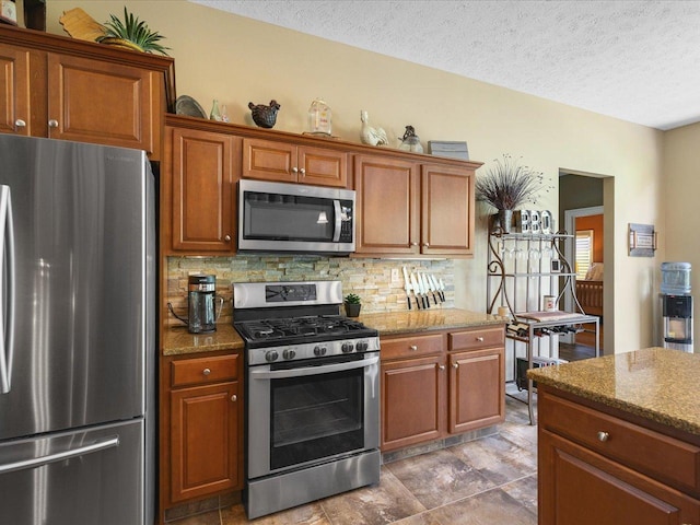7681 Highlands Dr, Rockford, IL 61102 - kitchen with appliances with stainless steel finishes, tasteful backsplash, brown cabinets, and a textured ceiling