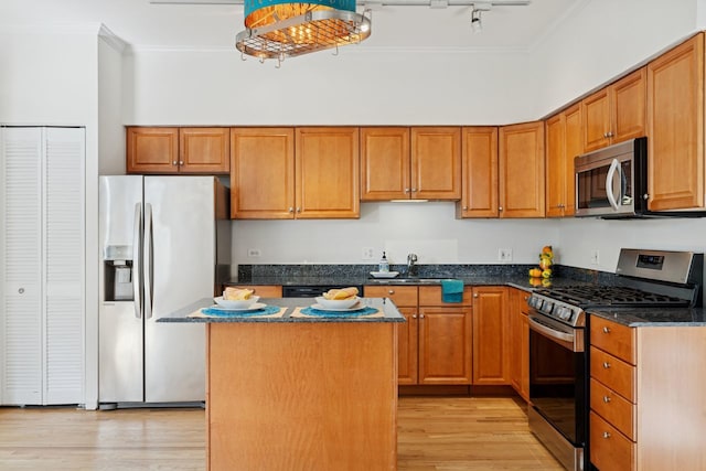 1023 W Balmoral Ave Unit 3A, Chicago, IL 60640 - kitchen featuring appliances with stainless steel finishes, crown molding, light wood-type flooring, a center island, and dark stone counters