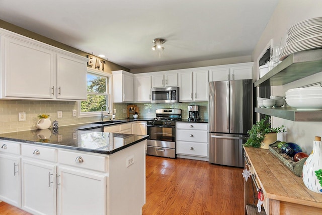 105 Devonshire Dr, Dekalb, IL 60115 - kitchen featuring appliances with stainless steel finishes, a peninsula, white cabinets, light wood-style flooring, and backsplash