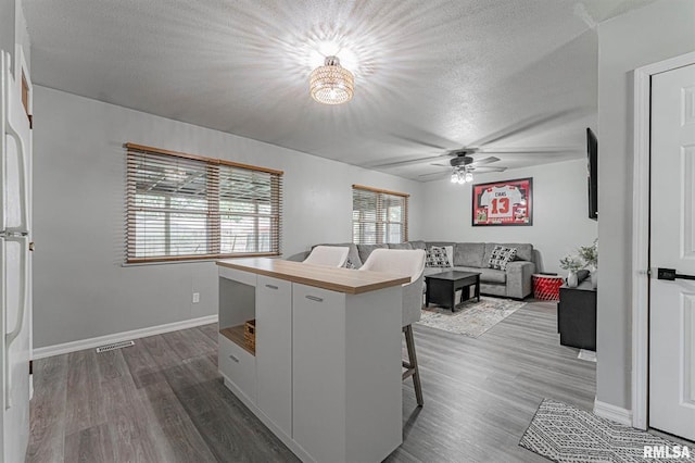 145 White Ave, Lincoln, IL 62656 - kitchen featuring a textured ceiling, a ceiling fan, dark wood-style floors, a chandelier, and a kitchen bar