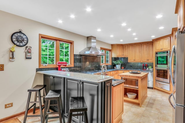 330 Dorchester Ln, Grayslake, IL 60030 - kitchen with wall chimney exhaust hood, appliances with stainless steel finishes, a warming drawer, a peninsula, and decorative backsplash