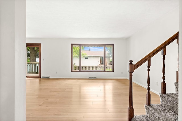 1219 Nicki Dr, Bloomington, IL 61704 - unfurnished living room with plenty of natural light, stairs, and light wood-style floors
