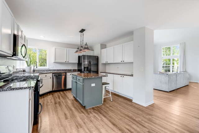 1356 Geneva Ln, Cary, IL 60013 - kitchen with appliances with stainless steel finishes, light wood-style floors, white cabinetry, a center island, and a breakfast bar area