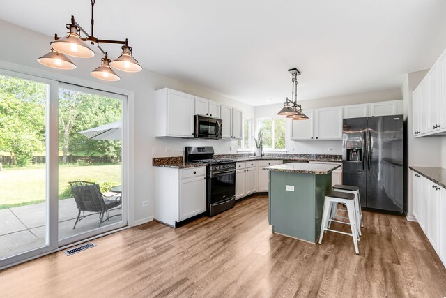 1356 Geneva Ln, Cary, IL 60013 - kitchen with refrigerator with ice dispenser, black gas range oven, stainless steel microwave, light wood finished floors, and a center island