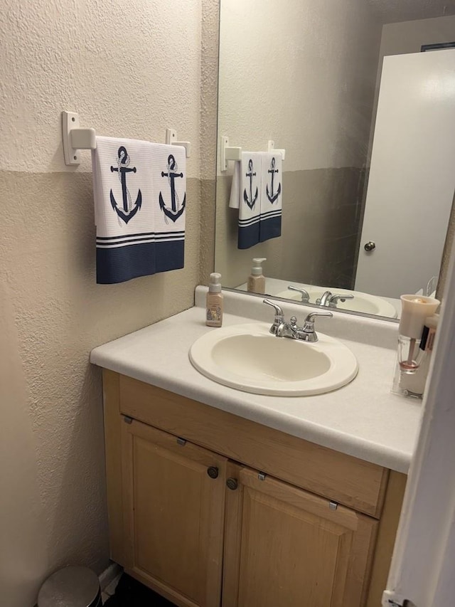 half bath featuring a textured wall and vanity