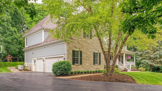 25660 N Countryside Dr, Lake Barrington, IL 60010 - view of front facade with stone siding, an attached garage, driveway, a front yard, and covered porch