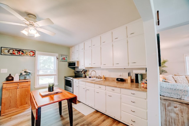 240 E 3rd Ave, Clifton, IL 60927 - kitchen with stainless steel appliances, light wood-type flooring, light countertops, white cabinetry, and a ceiling fan